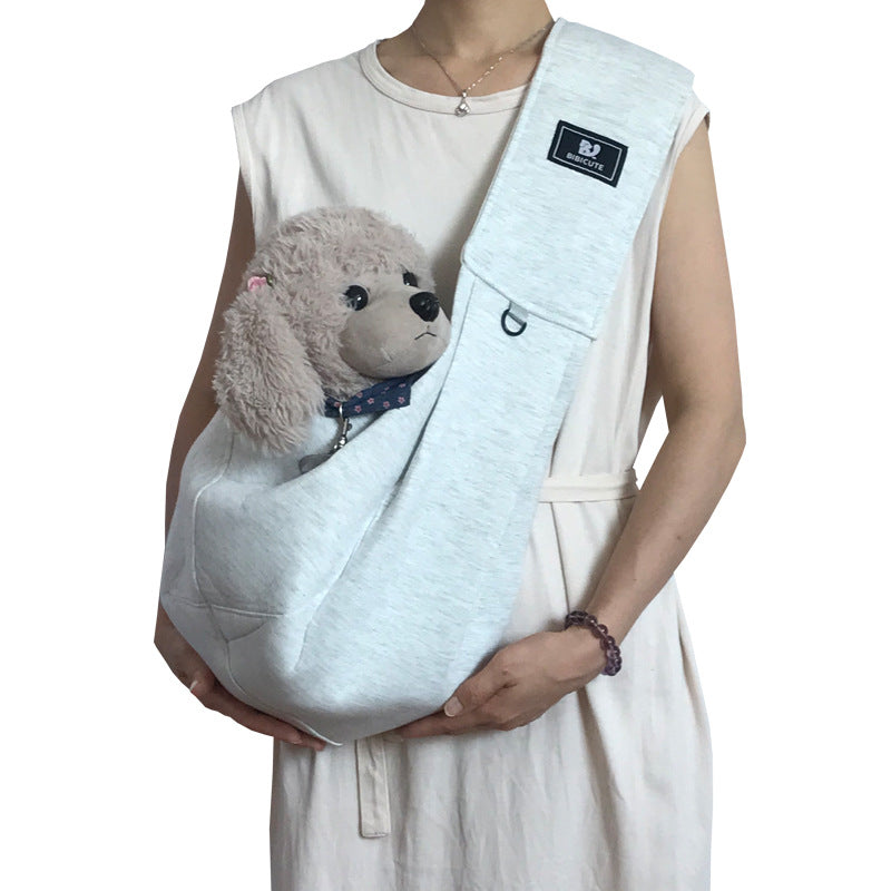 Person holding a small dog in a white pet sling against a white background