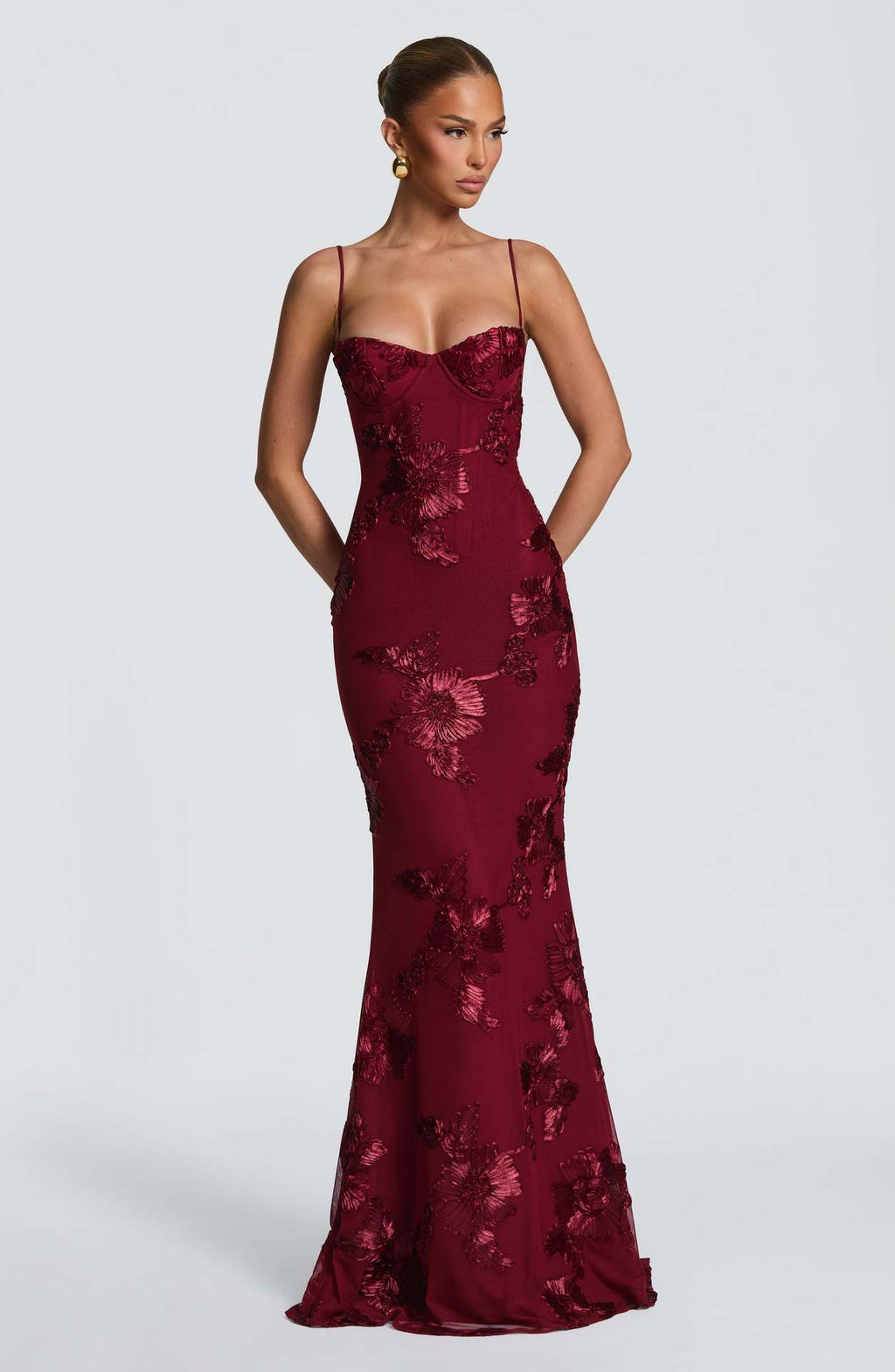 Burgundy floral evening gown on a model against a white background
