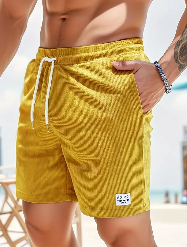 Yellow shorts with a brand logo worn by a person on a beach.