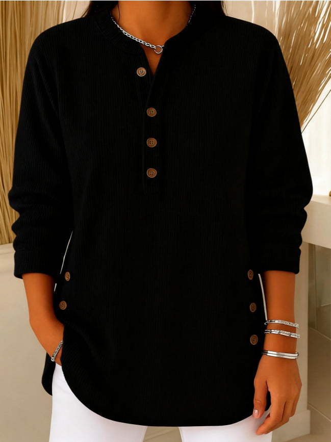 Person wearing a black long-sleeve shirt with buttons, standing against a neutral background.