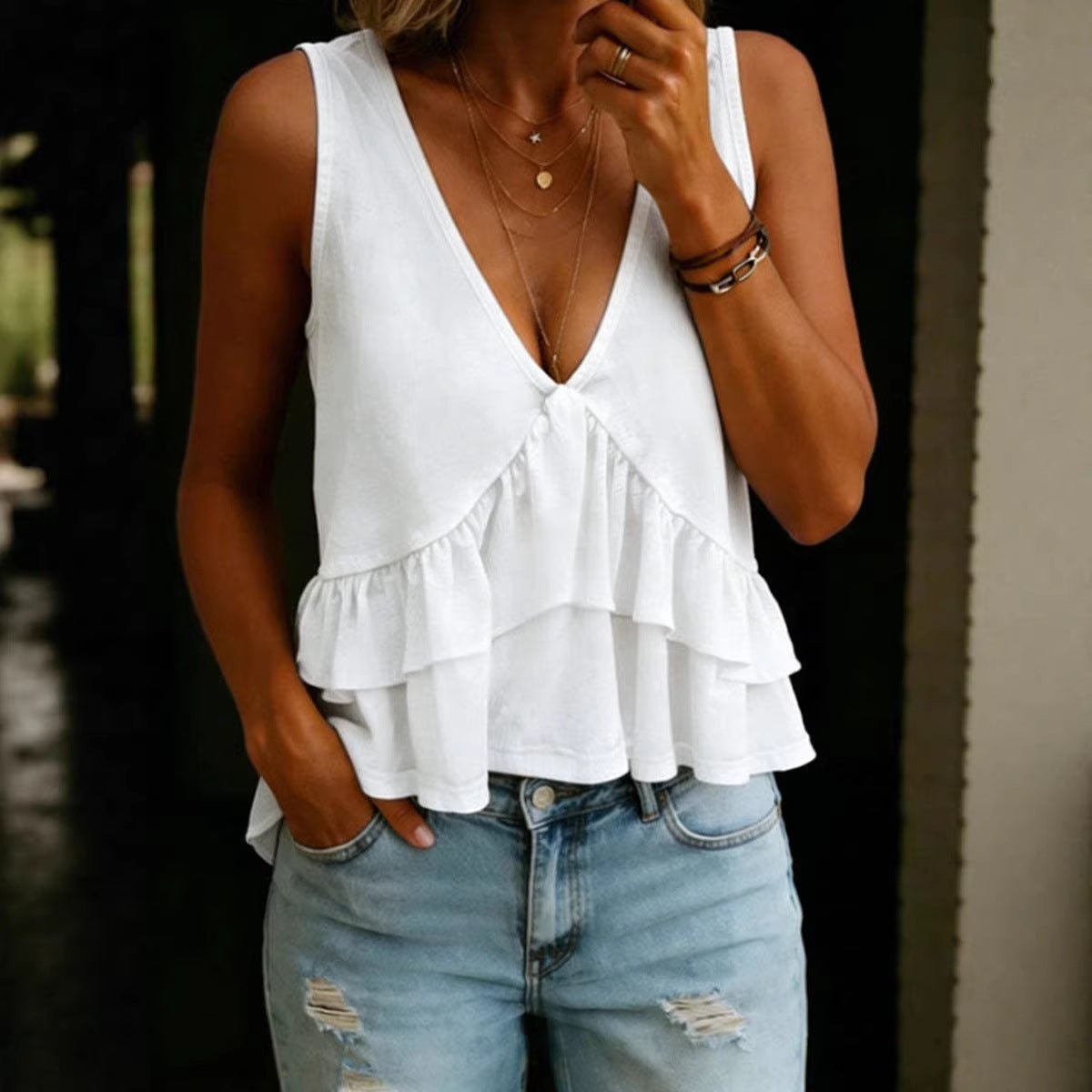 Person wearing a white ruffled top and blue jeans with a blurred background