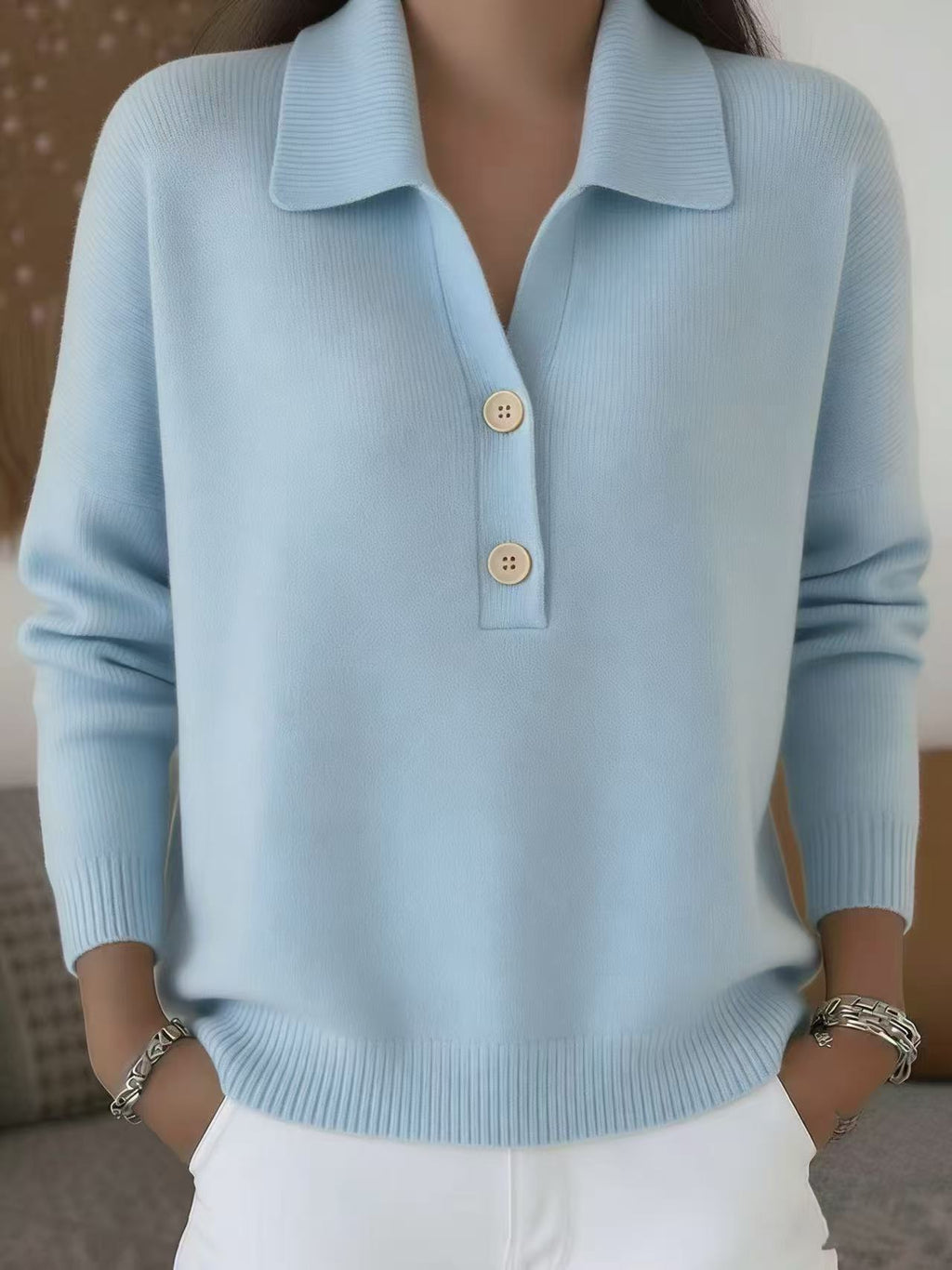 Light blue sweater with button details worn by a person, blurred background