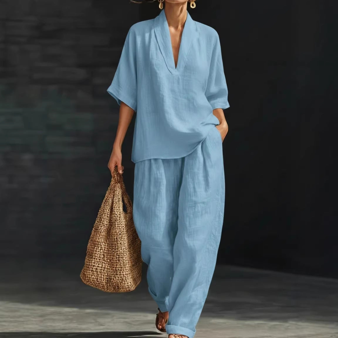 Person wearing a blue outfit holding a woven bag against a dark background