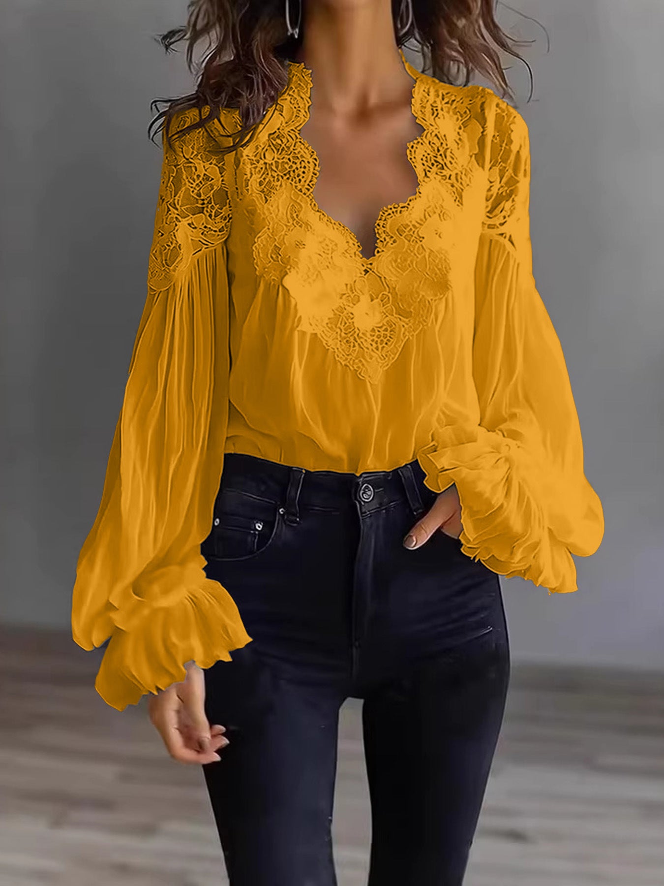 Yellow lace blouse with long sleeves worn by a person against a neutral background