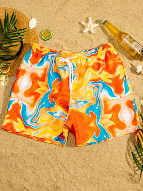 Colorful swim shorts on a sandy beach with a straw hat, lime, and starfish.