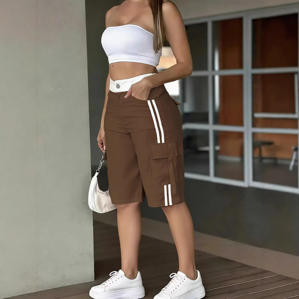 Person wearing a white crop top and brown cargo shorts with white stripes, standing indoors.