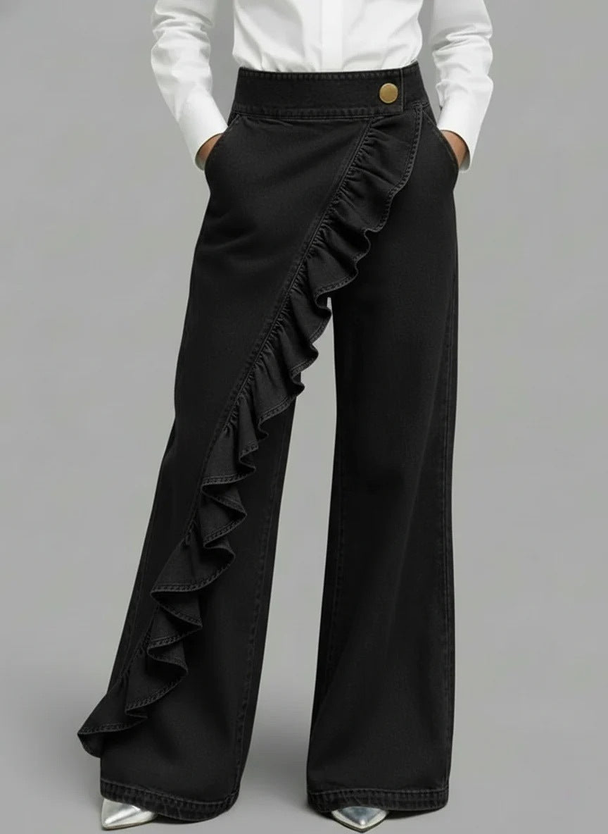 Black ruffled pants worn with a white shirt on a gray background