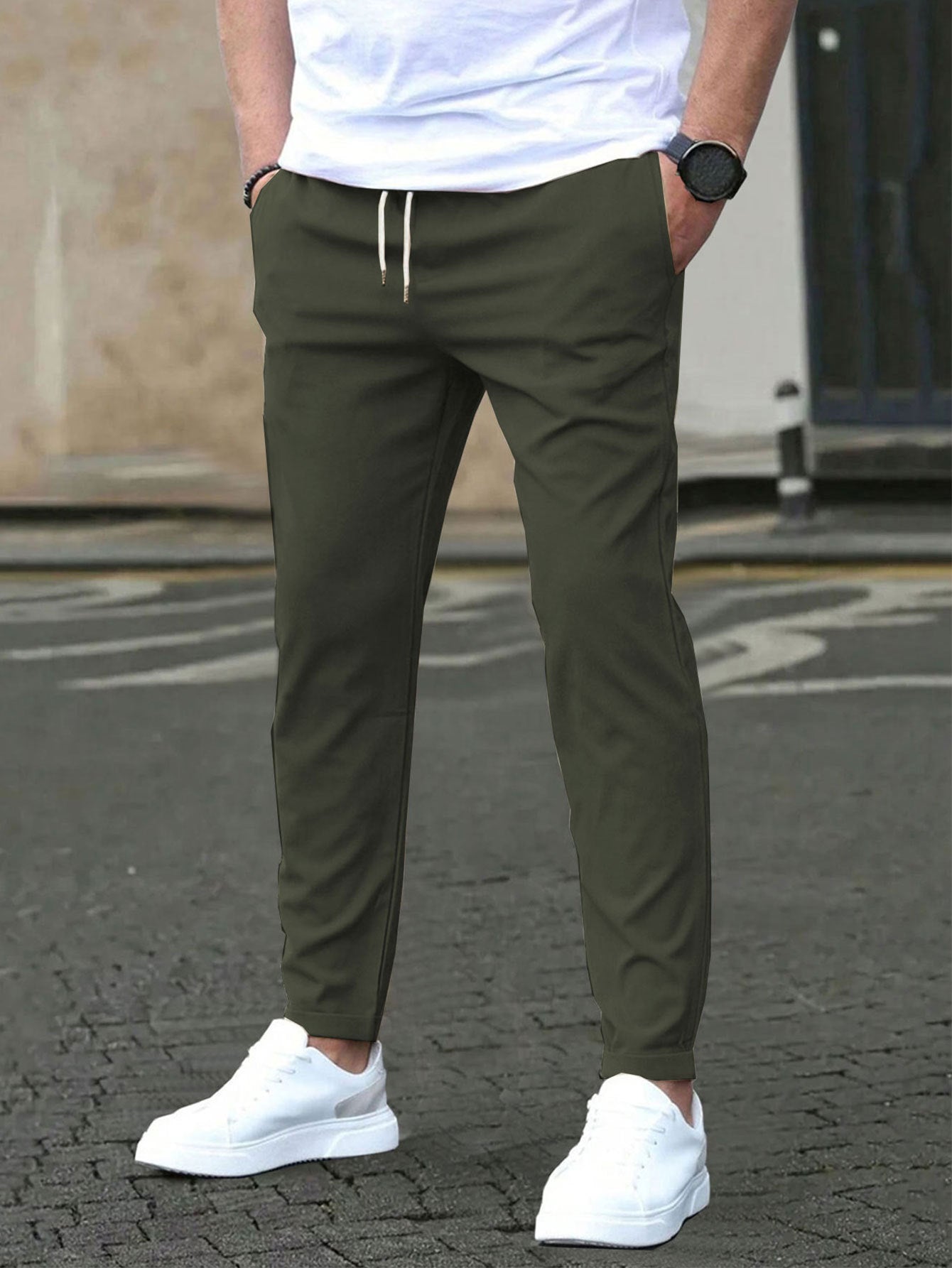 Person wearing olive green pants and white sneakers on a street.