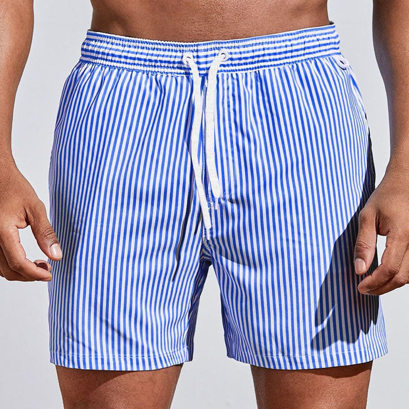 Blue and white striped swim shorts on a person against a light gray background