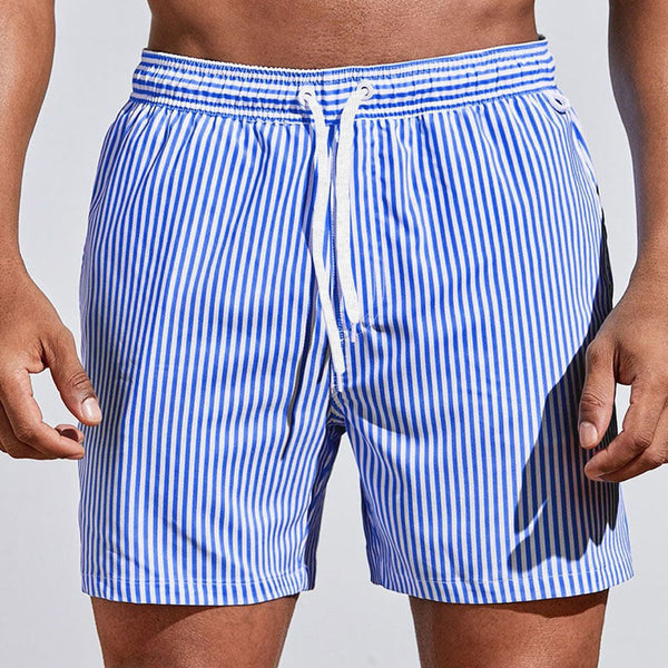 Blue and white striped swim shorts on a person against a light gray background