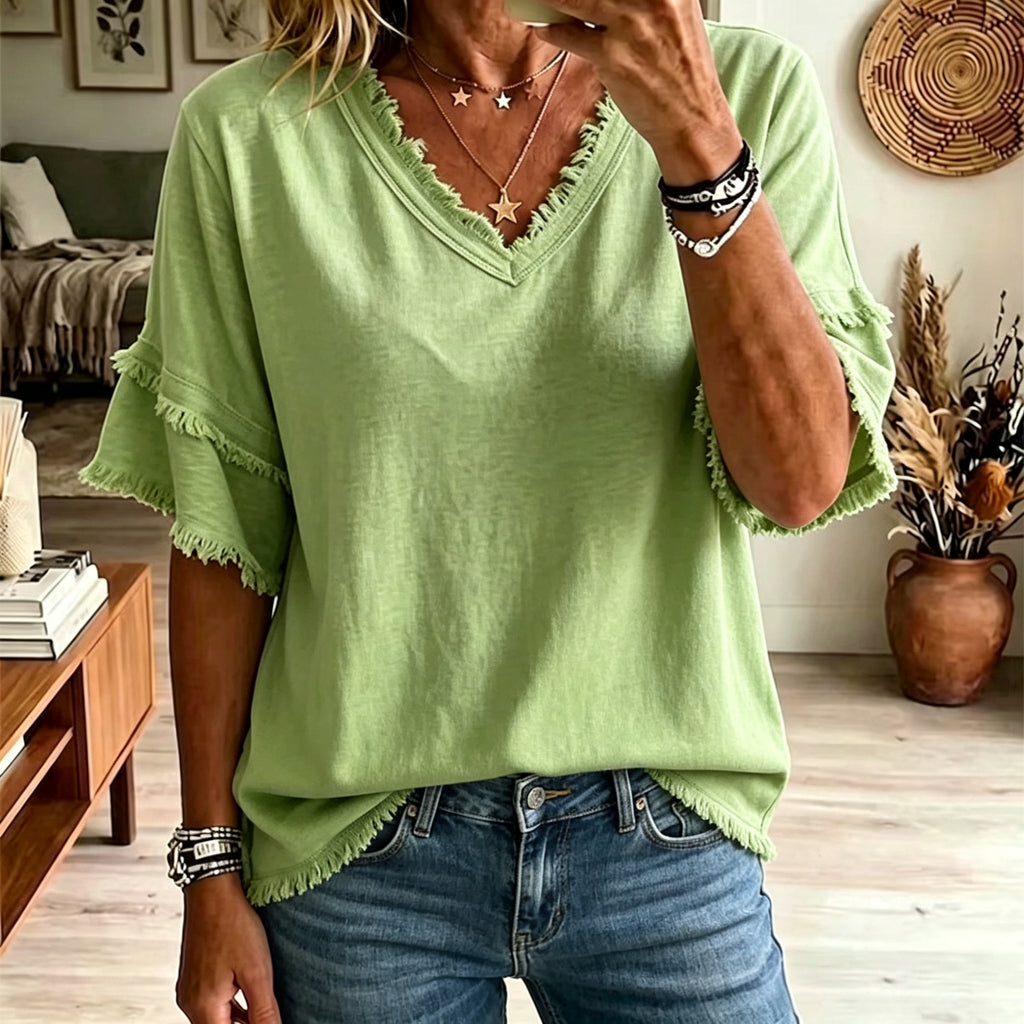 Person wearing a green top with fringe details in a living room setting