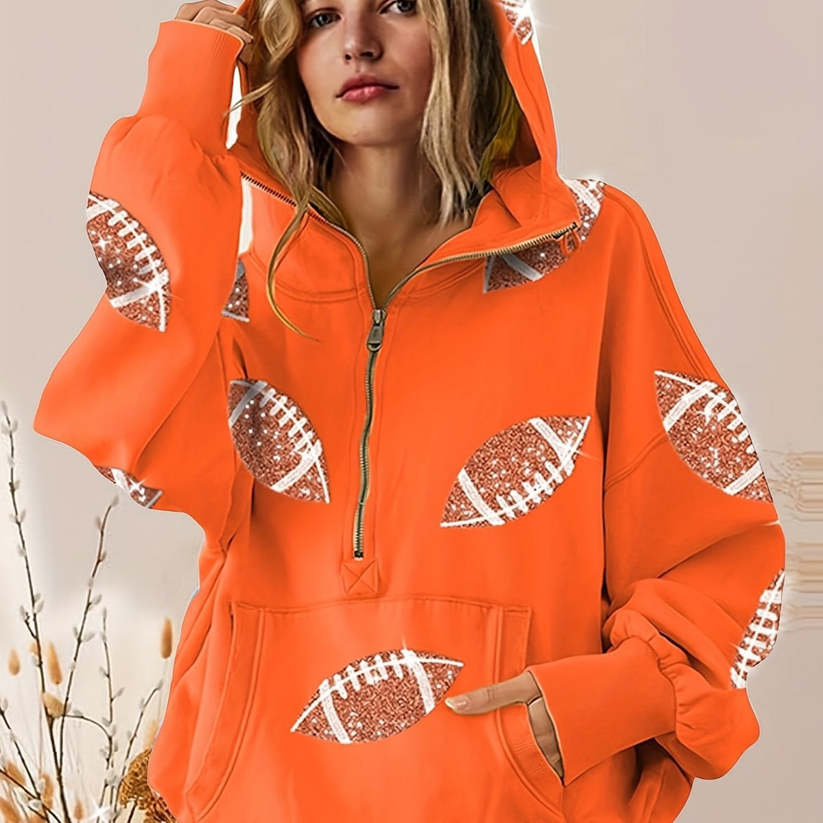 Orange hoodie with football designs on a neutral background