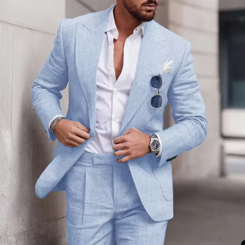 Man wearing a light blue suit with a white shirt, standing against a neutral background.