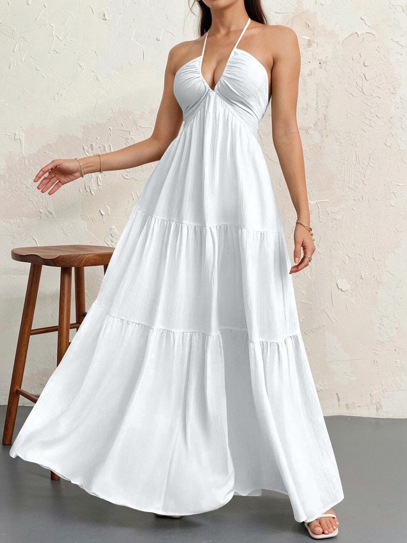 Woman wearing a white halter neck dress against a plain background