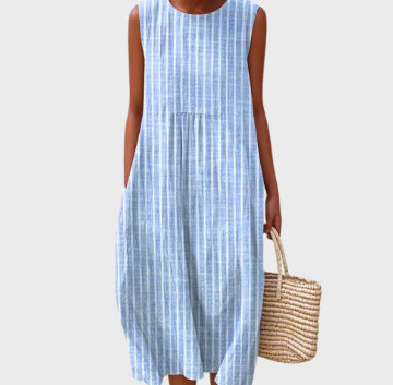 Woman wearing a blue and white checkered dress holding a straw bag on a light gray background