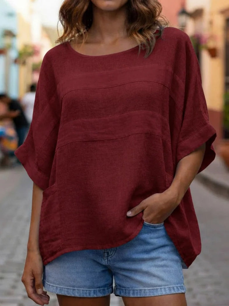 Person wearing a burgundy oversized shirt and denim shorts on a blurred street background