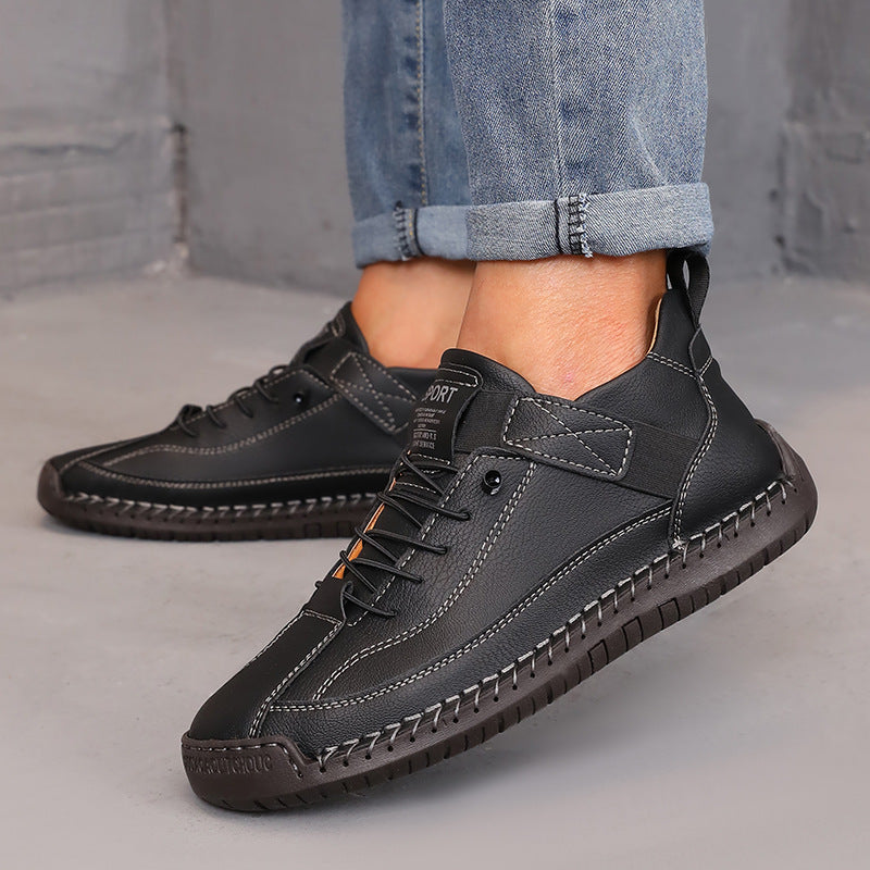 Black leather shoes worn with rolled-up jeans on a neutral background