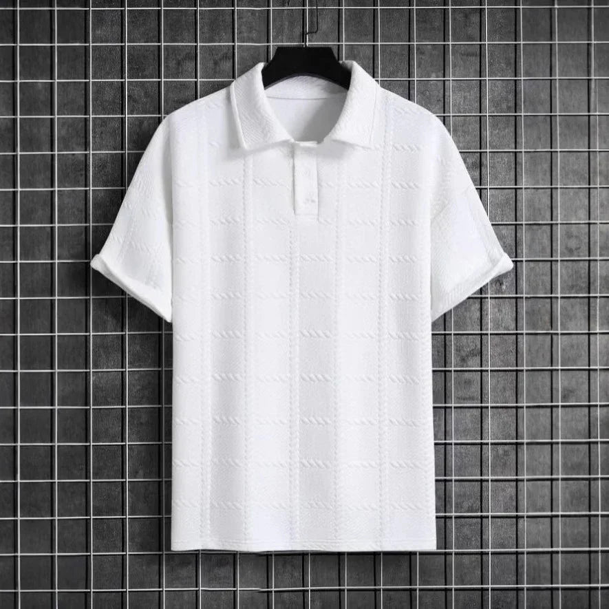 White short-sleeve shirt on a hanger against a black tiled wall.
