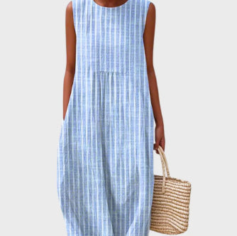 Woman wearing a blue and white striped dress holding a woven bag on a light gray background