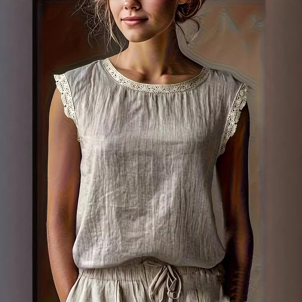 Woman wearing a light gray sleeveless top with lace trim against a neutral background