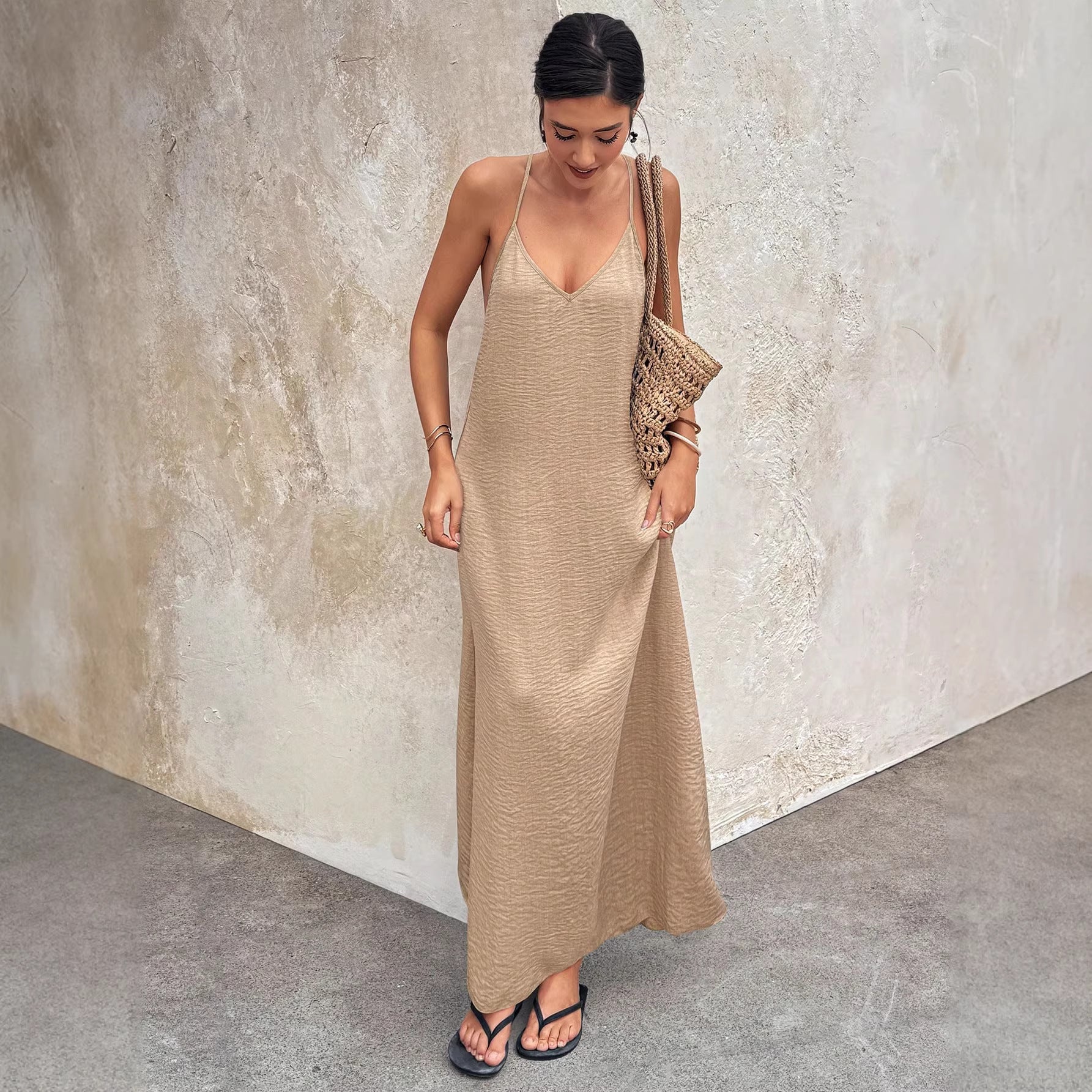 Woman wearing a beige slip dress against a textured wall.