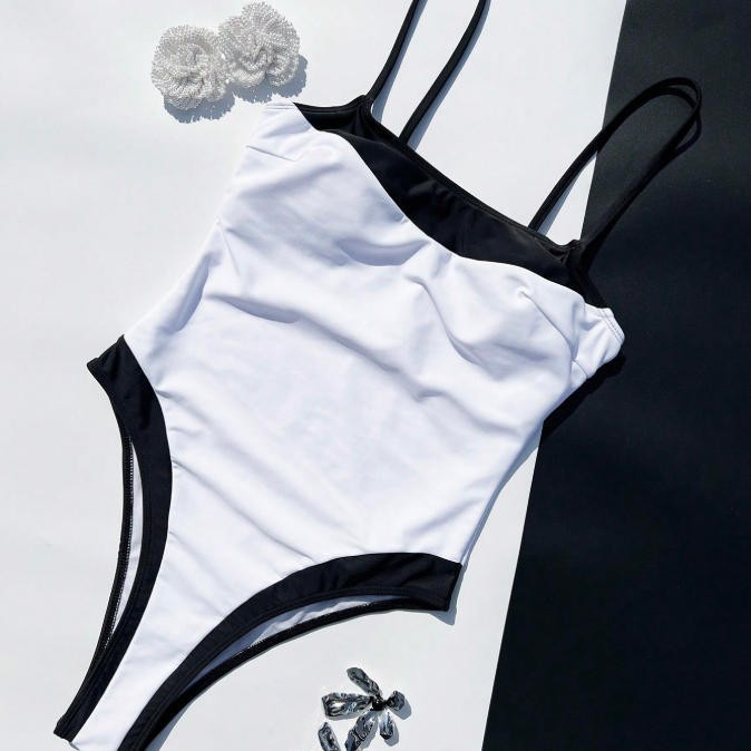 White swimsuit with black straps and trim on a white background