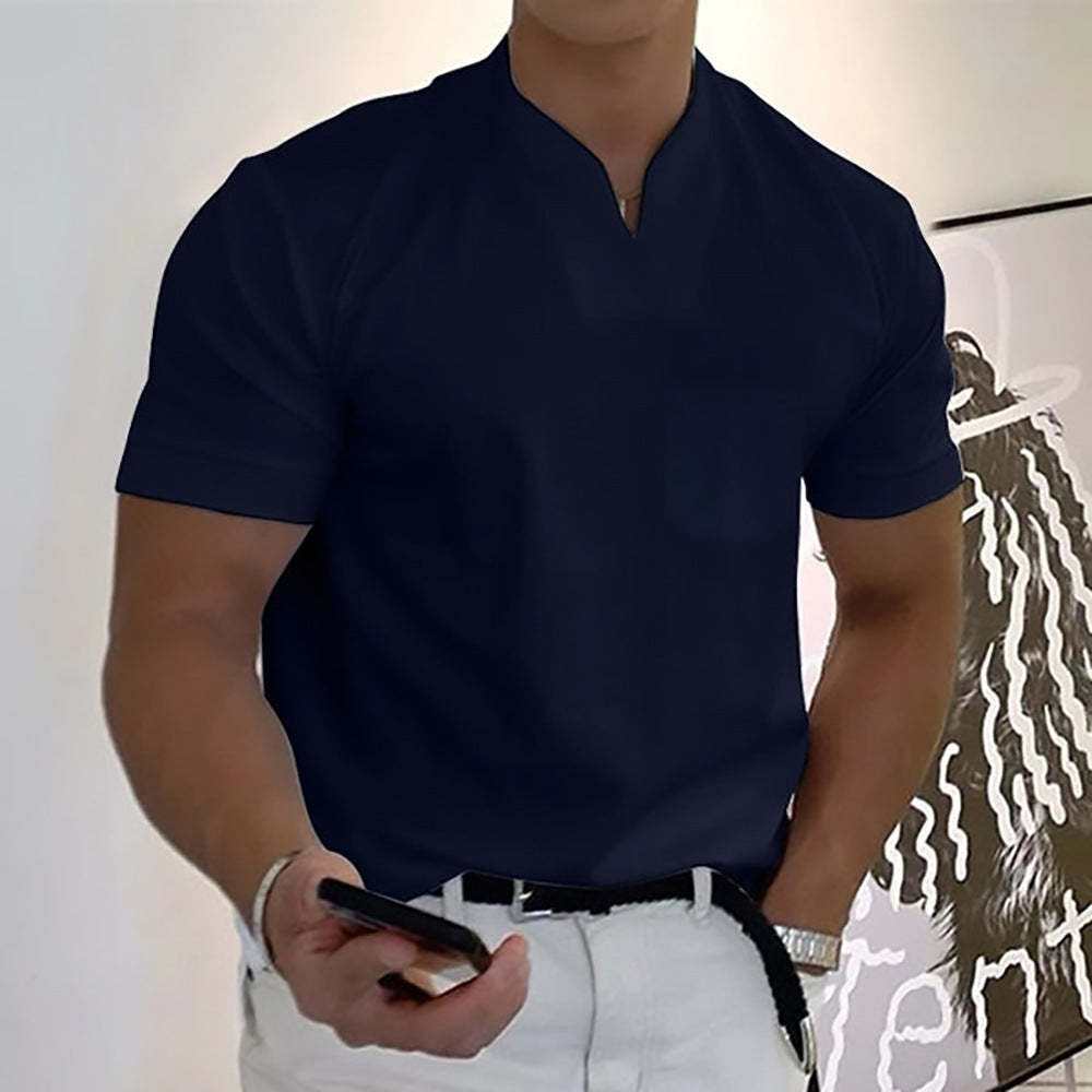 Person wearing a navy blue shirt and white pants holding a phone indoors.