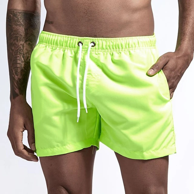 Bright green swim shorts with a white drawstring on a plain background