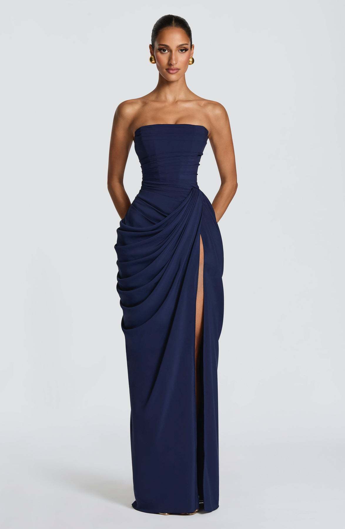 Navy strapless gown with a slit on a white background