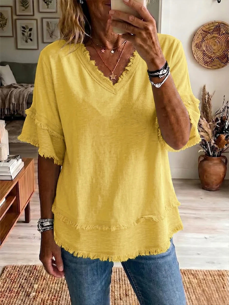 Person wearing a yellow blouse with ruffled sleeves in a living room setting.