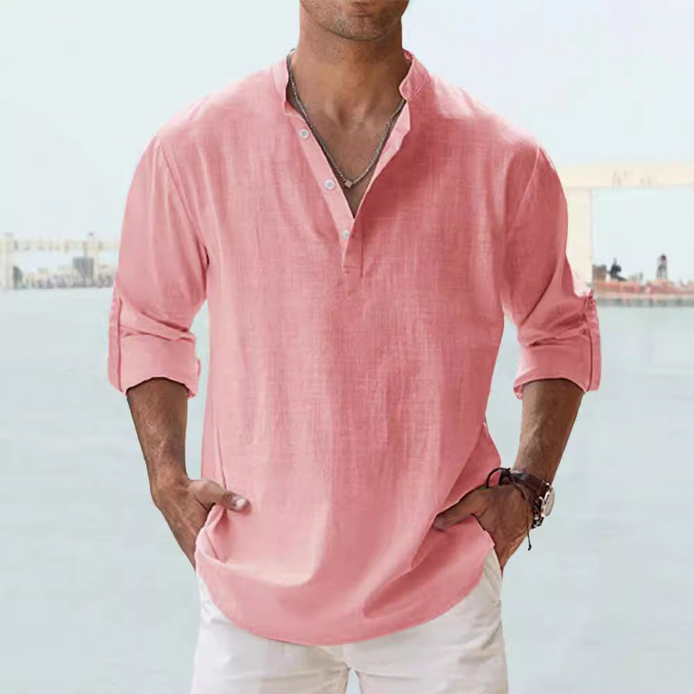 Man wearing a pink shirt with rolled-up sleeves against a blurred background