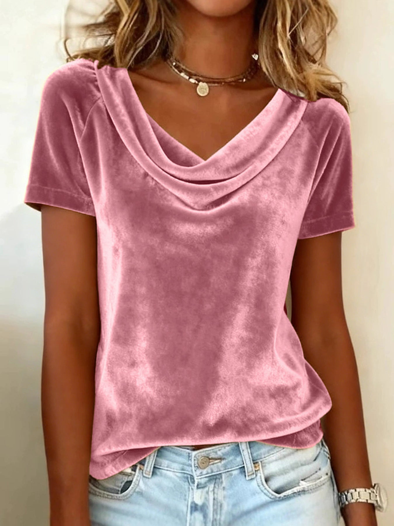 Person wearing a pink velvet top and light blue jeans against a plain background