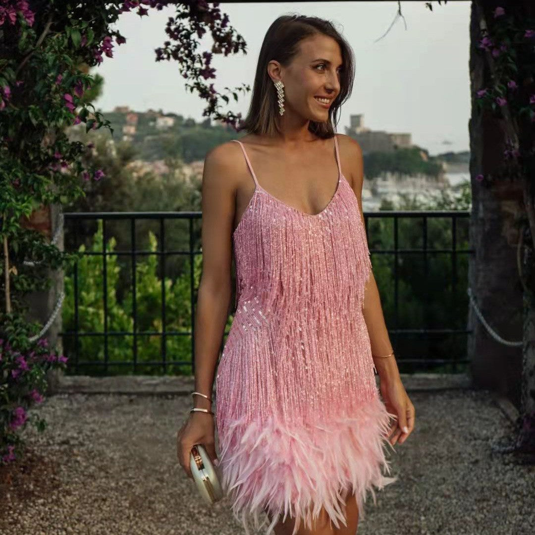 Woman wearing a pink fringe dress standing outdoors with greenery in the background