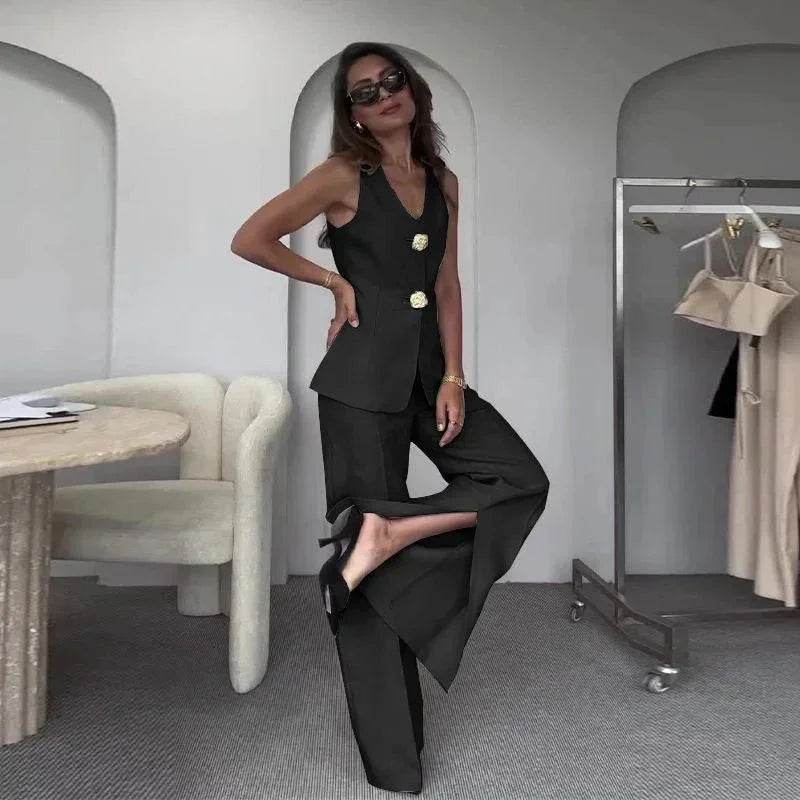 Woman in a stylish black pantsuit with gold buttons, posing in a chic ZA-Zola showroom.