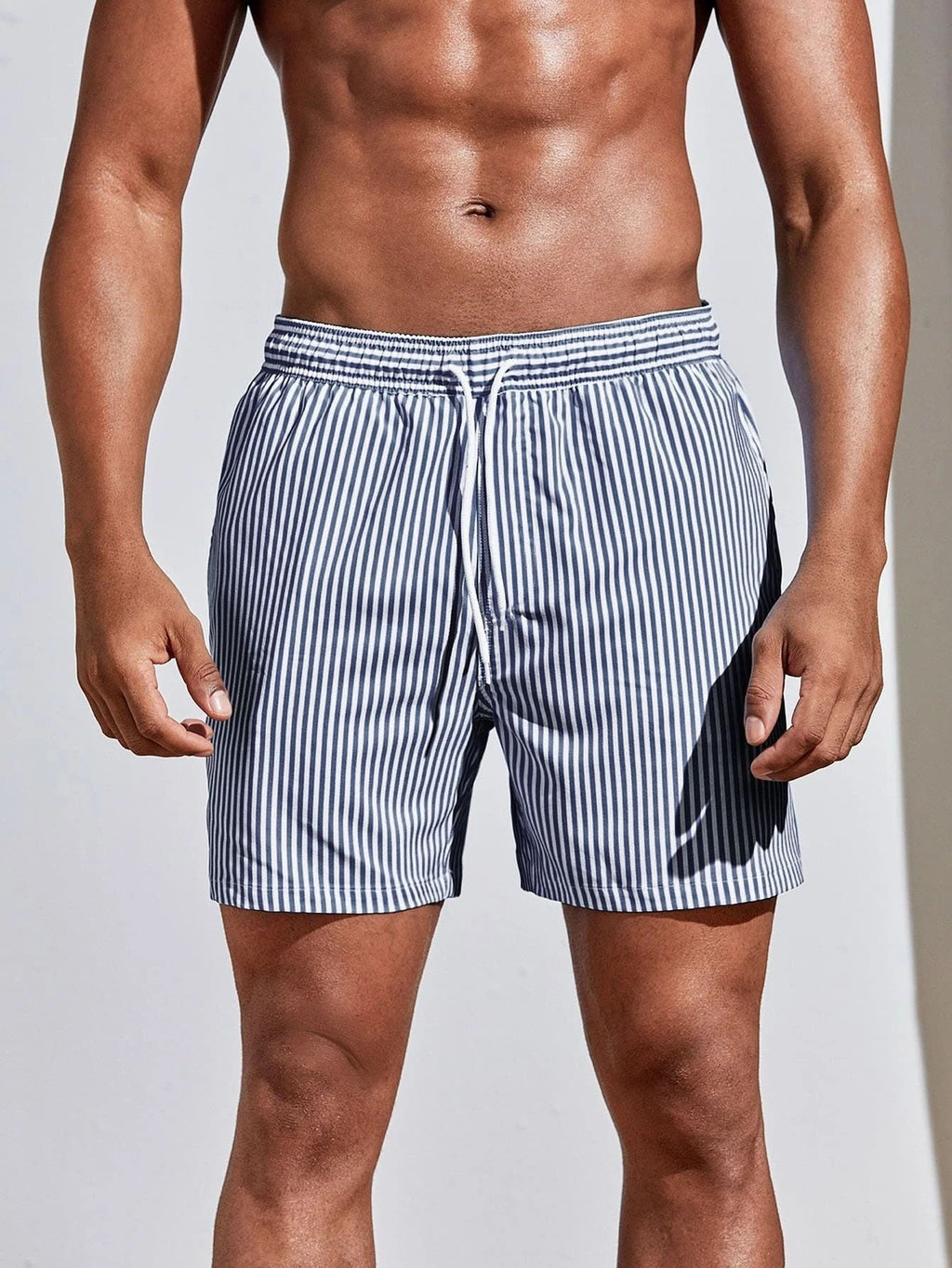 Man wearing striped swim shorts on a plain background