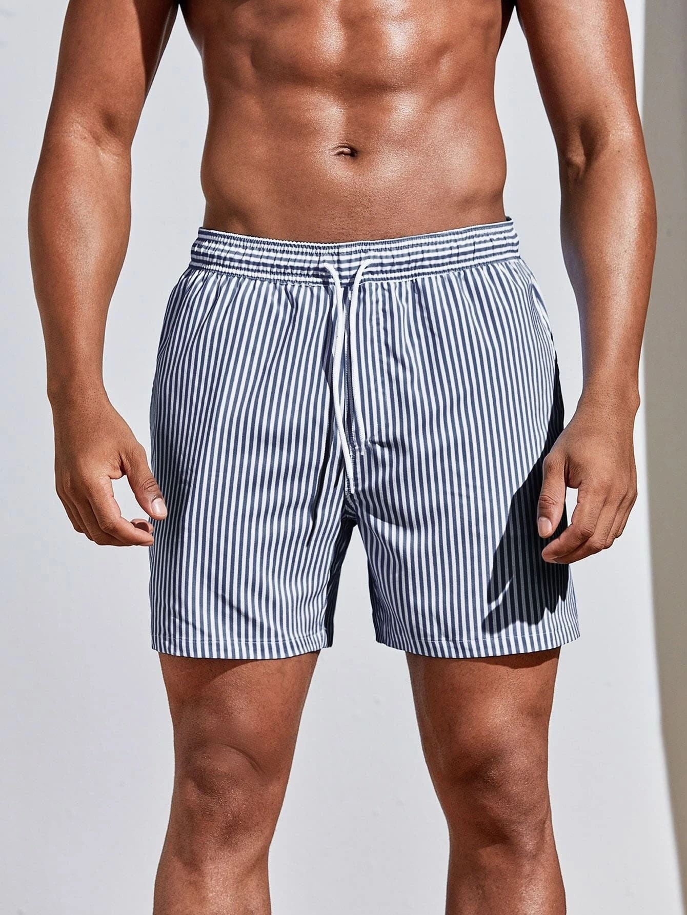 Man wearing striped swim shorts on a plain background