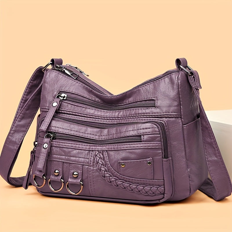 Purple leather handbag with multiple pockets and straps on a beige background