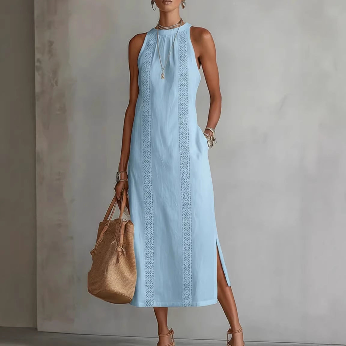 Woman wearing a light blue dress with intricate patterns, holding a beige handbag against a neutral background.