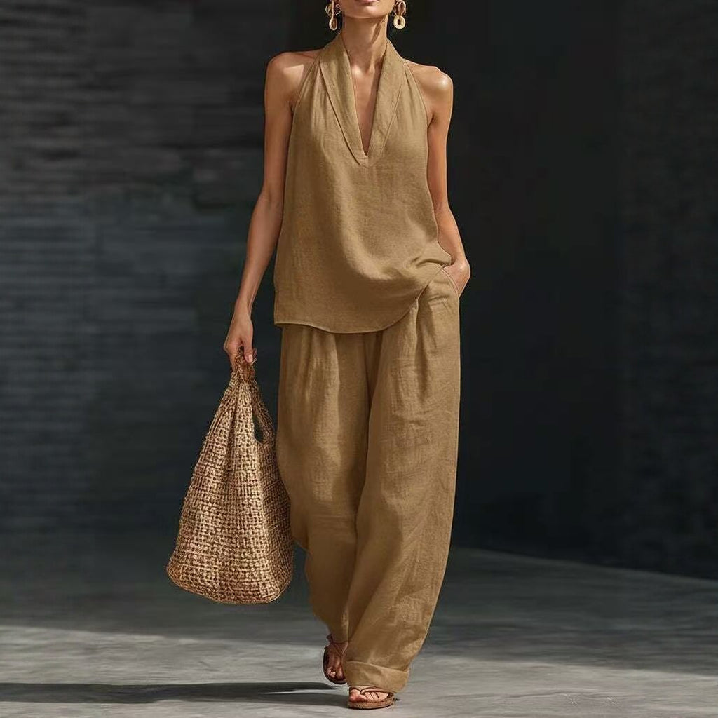 Woman wearing a beige outfit holding a woven bag against a dark background