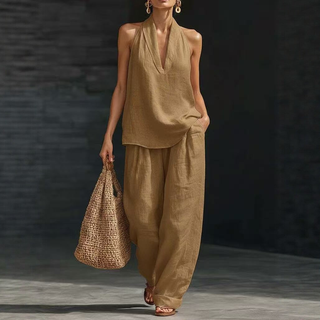 Woman wearing a beige outfit holding a woven bag against a dark background