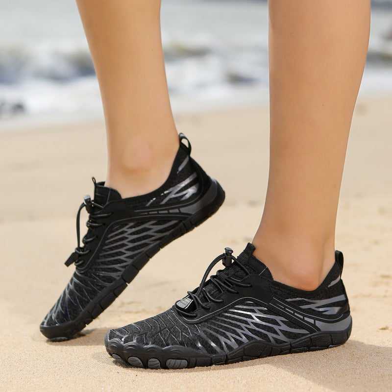 Black athletic shoes with a unique pattern worn on a sandy surface