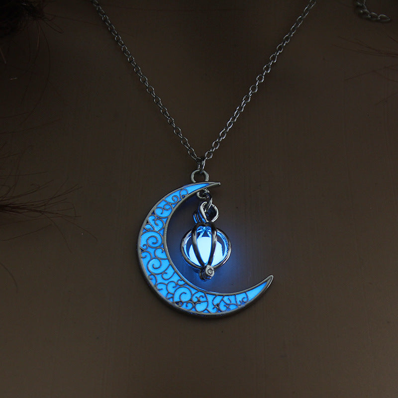 Glowing blue moon and star pendant on a chain against a dark background