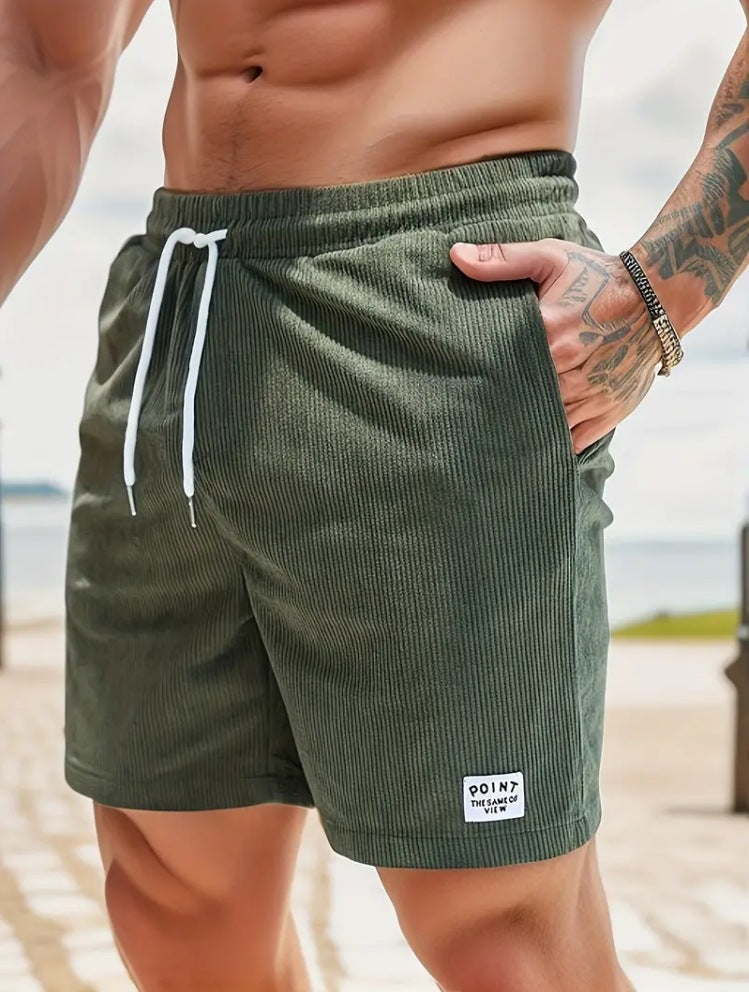 Person wearing green shorts with a brand logo on a beach