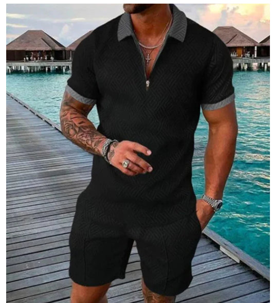 Man wearing a black textured polo shirt and shorts on a wooden dock with water and buildings in the background.