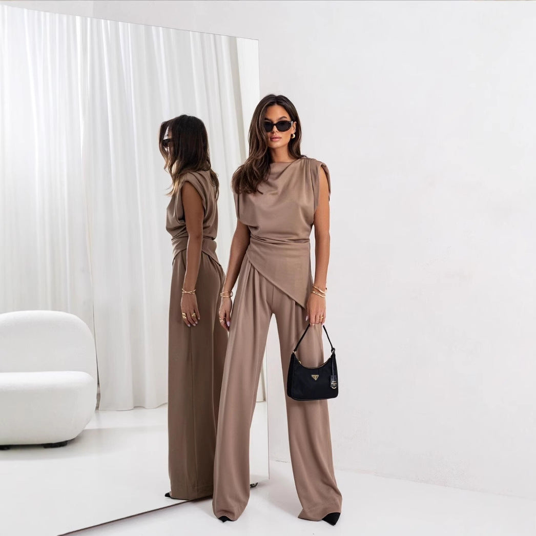Woman in a beige outfit standing in front of a mirror in a minimalistic room.