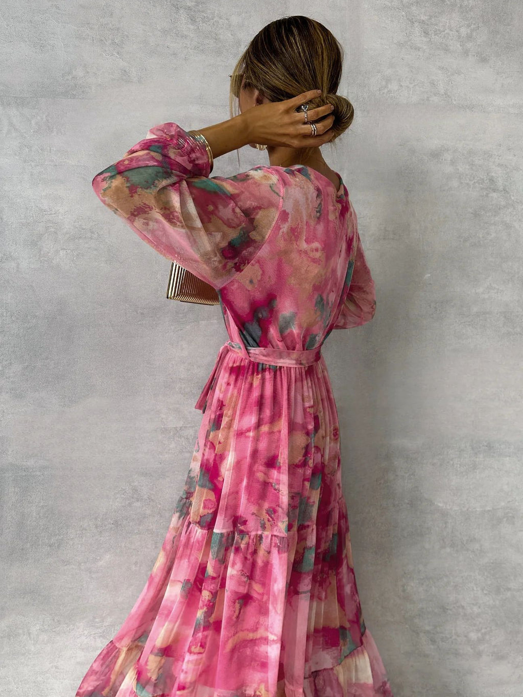 Woman wearing a pink floral dress against a gray background