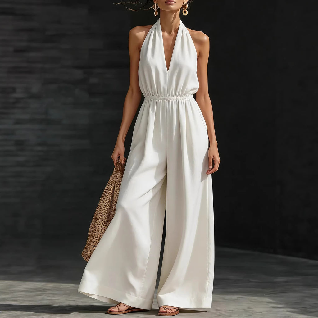 Woman wearing a white jumpsuit holding a woven bag against a dark background