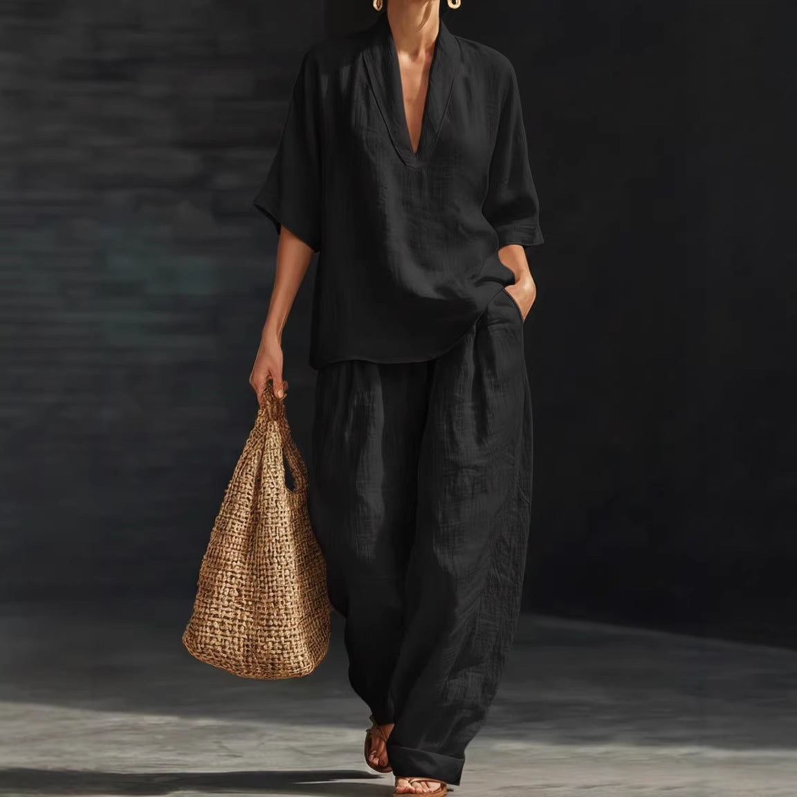 Person wearing a black outfit holding a woven bag against a dark background