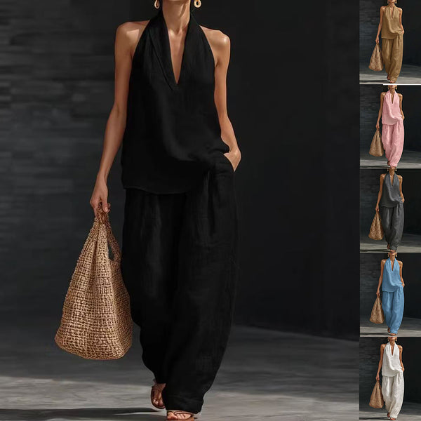 Woman in black outfit holding a woven bag against a dark background
