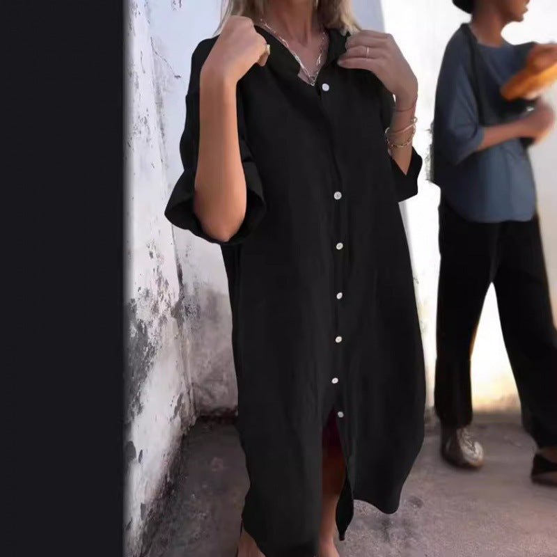 Person wearing a black button-up dress against a wall.
